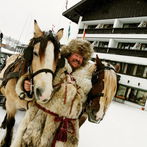 happy man in fur hat on horse sleigh outside Hotel Bardola, Norway