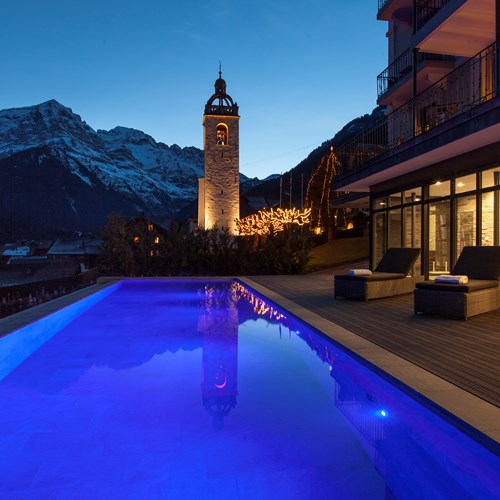Outdoor pool lit up at night Hotel National in Champery